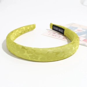 Dettaglio del cerchietto in spugna verde lime con tessuto jacquard floreale ed etichetta a mano