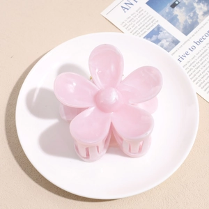 Close-up of pink flower hair claw clip with marble texture on a decorative plate