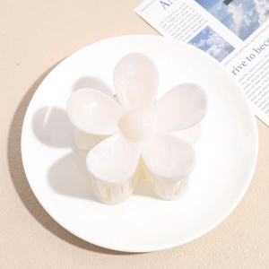 Detailed top view of cream-white flower hair claw clip with a glossy acetate finish