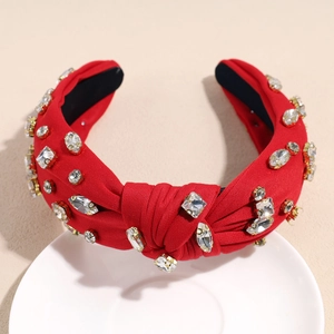 Détail du serre-tête noué rouge orné de strass brillants sertis sur métal doré