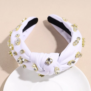 Détail d'un serre-tête noué blanc avec strass étincelants et supports dorés de luxe