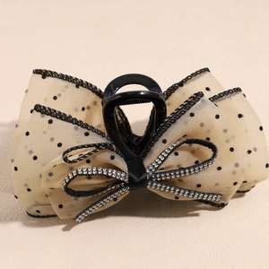 Détail de la pince à cheveux en tulle à pois beige avec petit nœud strass brillant