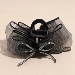 Détail de la pince à cheveux noire élégante avec nœud en maille grise et strass brillants