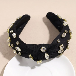 Détail d'un serre-tête noué baroque avec des strass variés sur une base en tissu noir