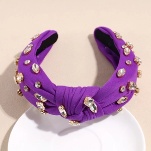 Détail d'un serre-tête nœud violet orné de strass sur une assiette blanche