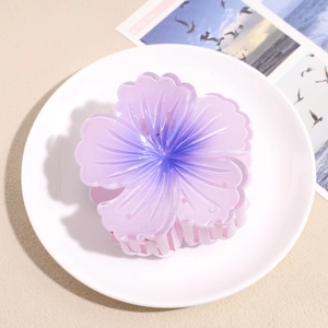 Macro detail of a large purple gradient plumeria hair claw clip on a white plate