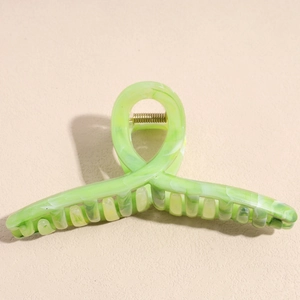 Macro shot of large acetate hair claw clip with light green marble texture and gold spring