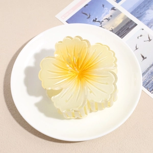 Detail of yellow flower hair claw clip with translucent jelly texture on a white plate