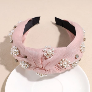 Close-up of pink twisted fabric headband featuring white pearls and rhinestone flowers