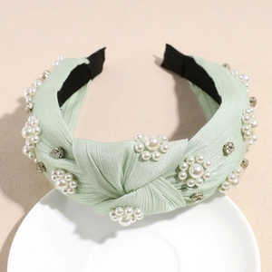 Detail of light green silk knot headband with white faux pearls and crystals on a tray