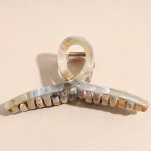 Detailed close-up of large marble texture hair claw clip with golden metal spring