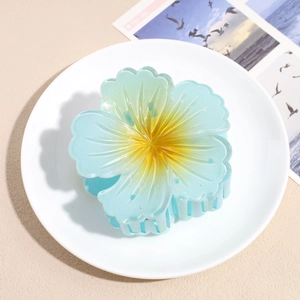 Detailed view of blue hibiscus flower hair claw with yellow center and resin petals
