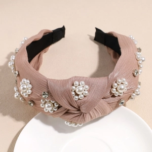 Detailed view of hand-sewn pearl flower clusters and rhinestones on pink knotted headband