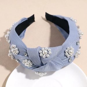Detail of light blue knotted headband featuring white pearl flowers and rhinestones