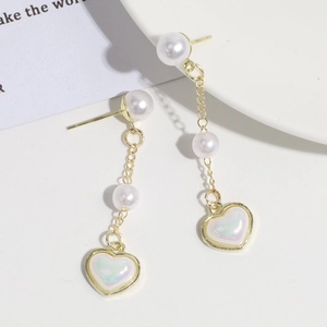 Detalle de los pendientes de cadena dorada con perlas blancas y colgantes de corazón