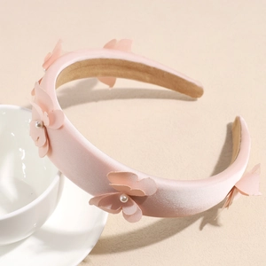 Close-up of pink padded bow headband with pearls resting on a white ceramic teacup