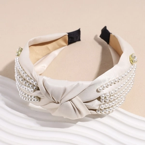 Detail of beige knotted headband with pearls and rhinestones on satin fabric