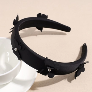 Detail of black bow headband with white pearls on a ceramic cup in a warm setting