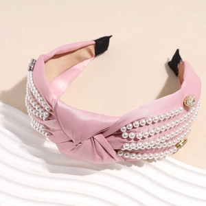 Detail of pink satin knotted headband featuring white pearls and rhinestone accents