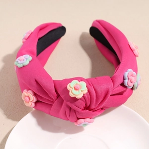 Détail d'un serre-tête rose rouge noué avec des ornements floraux colorés en résine 3D