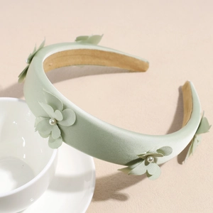 Detail view of mint green fabric headband with silk texture and elegant pearl floral accents