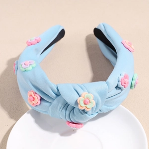 Détail d'un serre-tête noué bleu clair orné de petites fleurs 3D multicolores