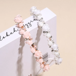Serre-têtes avec roses roses et blanches, perles et strass sur un livre déco