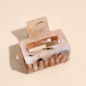 Close-up of rectangular cream hair claw clip with black ink splatter marble pattern