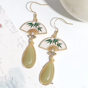 Detalle de pendientes de abanico dorado con motivo de bambú y colgante de lágrima