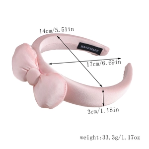 Détail du serre-tête nœud rose en satin montrant l'étiquette et les dimensions