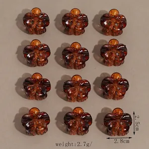 Dettaglio di 12 mini fermagli per capelli color ambra in resina trasparente con molla