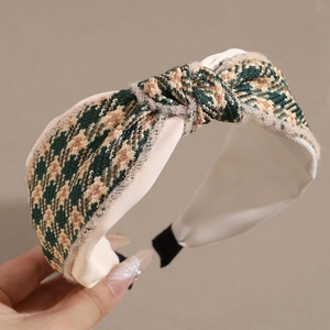 Close-up of houndstooth knotted headband featuring green and gold woven fabric texture