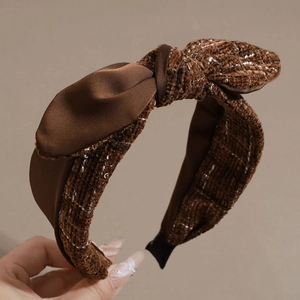 Detail eines braunen Schleifen-Haarreifens aus Satin und strukturiertem Tweed-Stoff