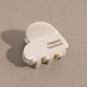 Detailed close-up of cream heart hair claw with golden France Handmade lettering