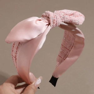 Nahaufnahme des rosa Tweed-Haarreifs mit Satinschleife zeigt Webstruktur und Glanzstoff