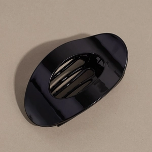 Vue détaillée d'une pince à cheveux ovale noire brillante au design incurvé lisse