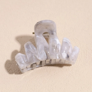 Detail of grey marble plastic hair claw clip with golden metal spring and glossy finish