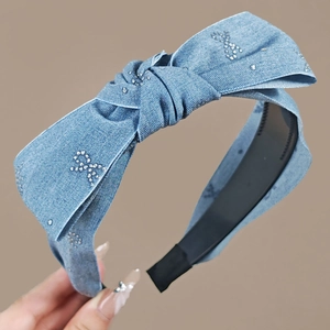 Détail d'un serre-tête en jean bleu clair avec grand nœud en strass et dents antidérapantes