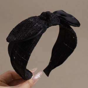 Detail eines schwarzen Tweed-Haarreif mit Pailletten und einer Satinschleife