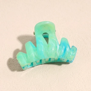 Close-up of green and blue marble texture on a plastic hair claw clip with matte finish