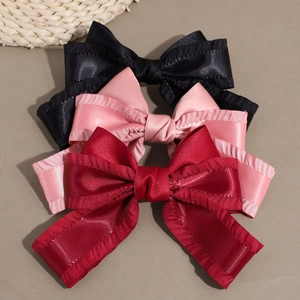 Detail von Satin-Haarschleifen in Schwarz, Rosa und Rot mit Rüschenkanten-Design