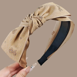 Vue détaillée d'un serre-tête nœud or beige avec ornements en strass étincelants