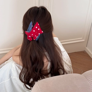 Detail view of red polka dot and navy denim bow hair claw clip on brunette wavy hair