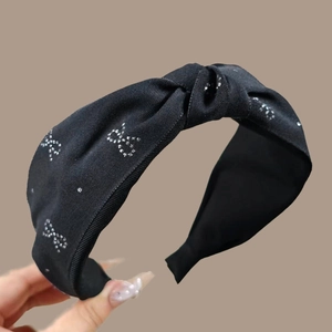 Détail du serre-tête en tissu noir avec motifs papillon argentés et design à nœud central