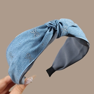 Détail d'un serre-tête en denim bleu clair avec motifs papillons en strass et nœud large