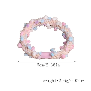 Detail view of a colorful pom-pom hair tie showing dimensions of 6cm and 2.6g weight