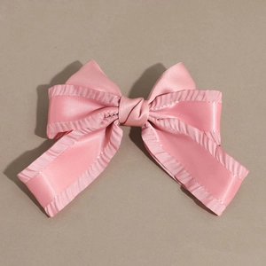 Detailansicht einer rosa Satin-Schleife Haarklammer mit Rüschenrand und Seidenglanz
