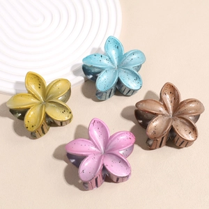 Detailed view of lily-shaped hair claws with matte finish and ink-splatter pattern