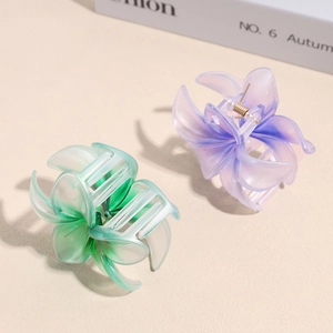 Close-up of matte lily flower hair clips in mint green and lavender purple gradient colors