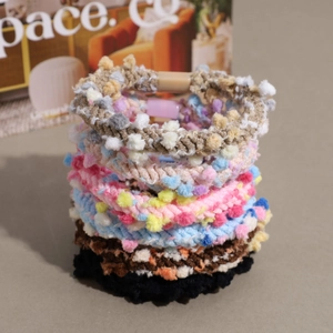 Set of colorful knitted hair ties with textured pom-poms on a rustic background